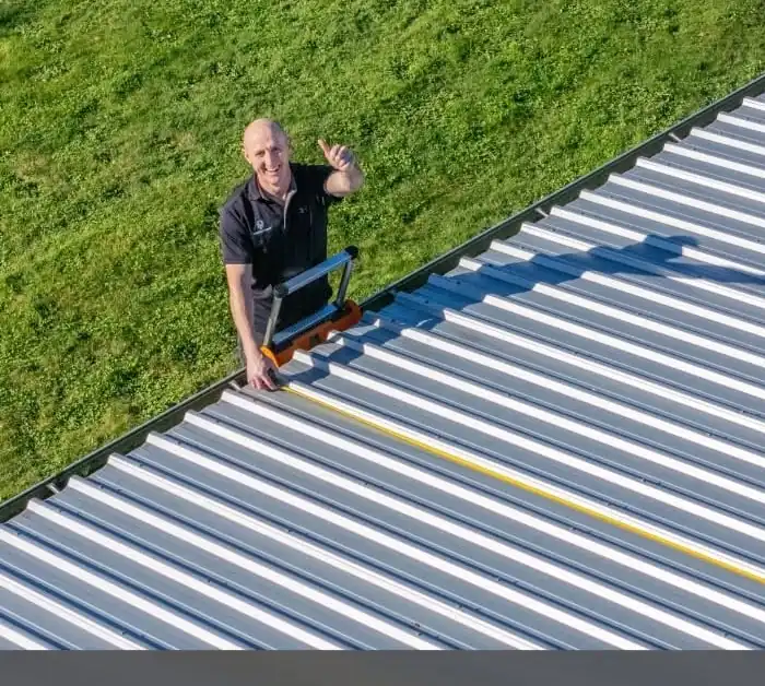 Energy Point technician on a ladder measuring a Waikato roof